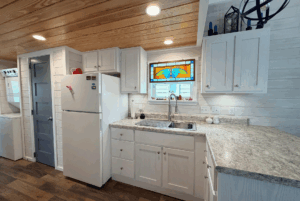 Compact kitchen with white cabinets, marble countertop, and stained-glass window at 44 Skipping Stone Lane.
