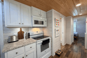 Modern kitchen with white cabinets, microwave, and wooden accents at 44 Skipping Stone Lane; bedroom visible in back.