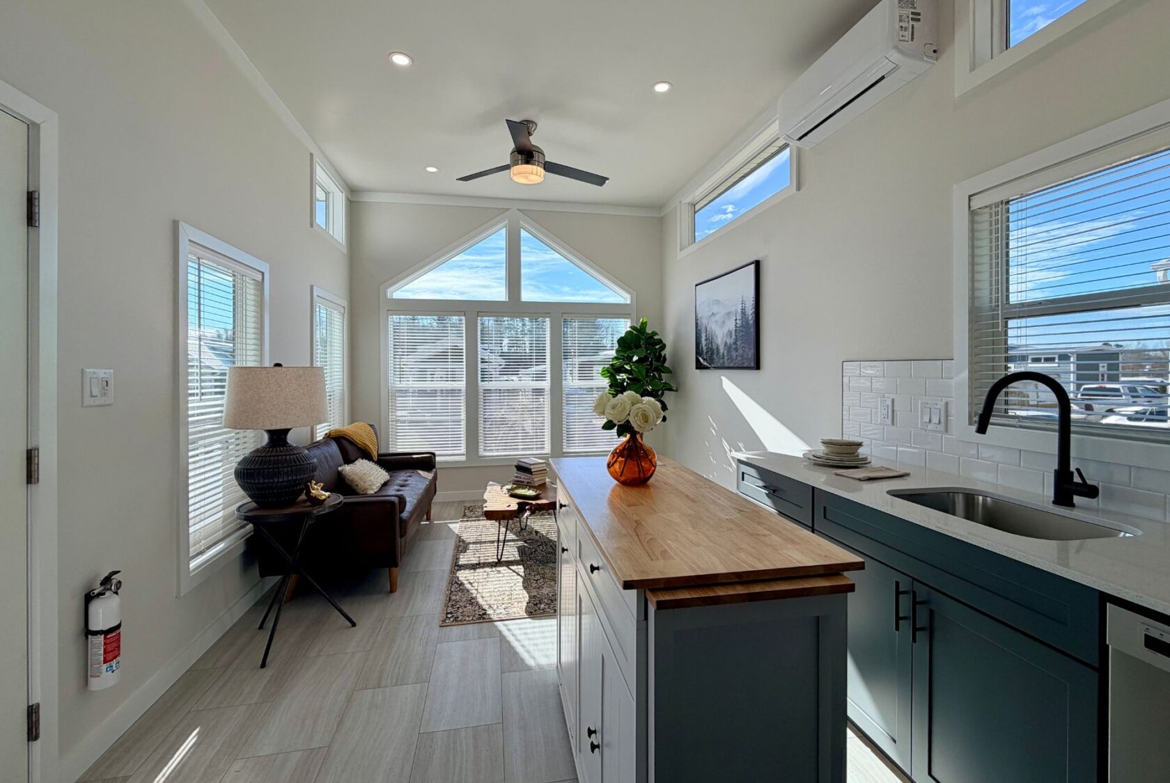 Bright, modern tiny home interior with large windows, kitchen island, and cozy living area.