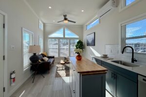 Bright, modern tiny home interior with large windows, kitchen island, and cozy living area.