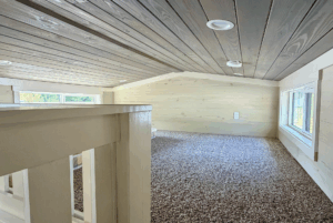 Cozy loft at Two Swans Lane with carpeted floor, wood-paneled ceiling, and plenty of natural light from windows.