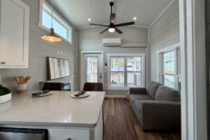 Bright tiny house interior at 124 Misty Knoll Way with a modern kitchen, gray sofa, and large windows.