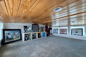 A cozy loft at 44 Skipping Stone Lane displays golf memorabilia, framed photos, trophies, and golf bags on carpeted flooring.