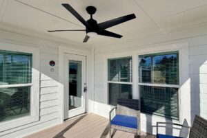 Relax on the covered patio featuring a ceiling fan, comfy chairs, and large sunny windows.