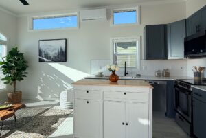 Bright kitchen with gray cabinets, white island, and sunlight streaming in.