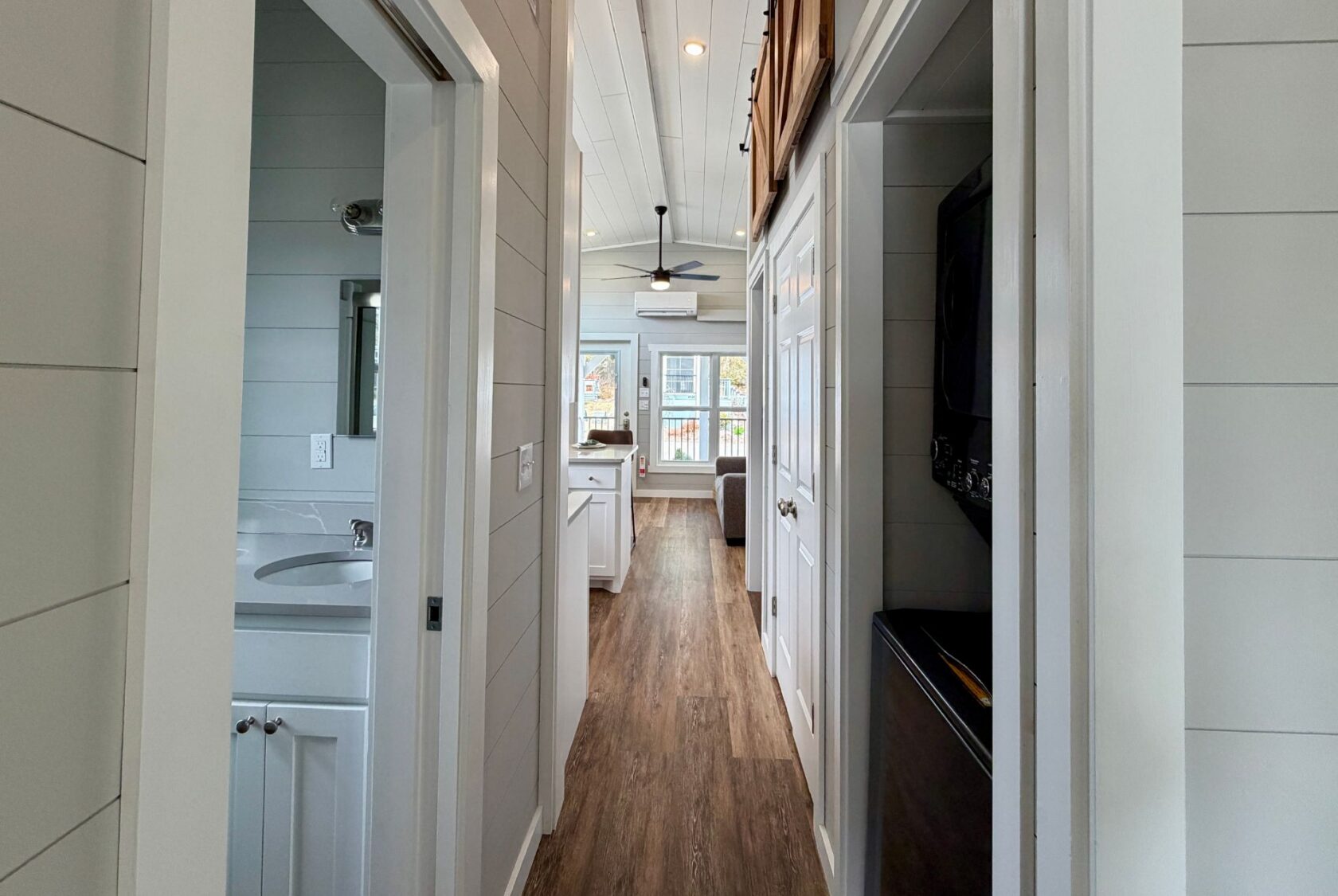 Hallway at 124 Misty Knoll Way: bathroom left, laundry right, leads to bright living room with ceiling fan.