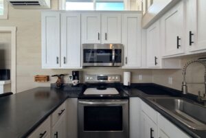 Modern white kitchen at Two Swans Lane with black countertops, stainless steel appliances, and stylish cabinetry.