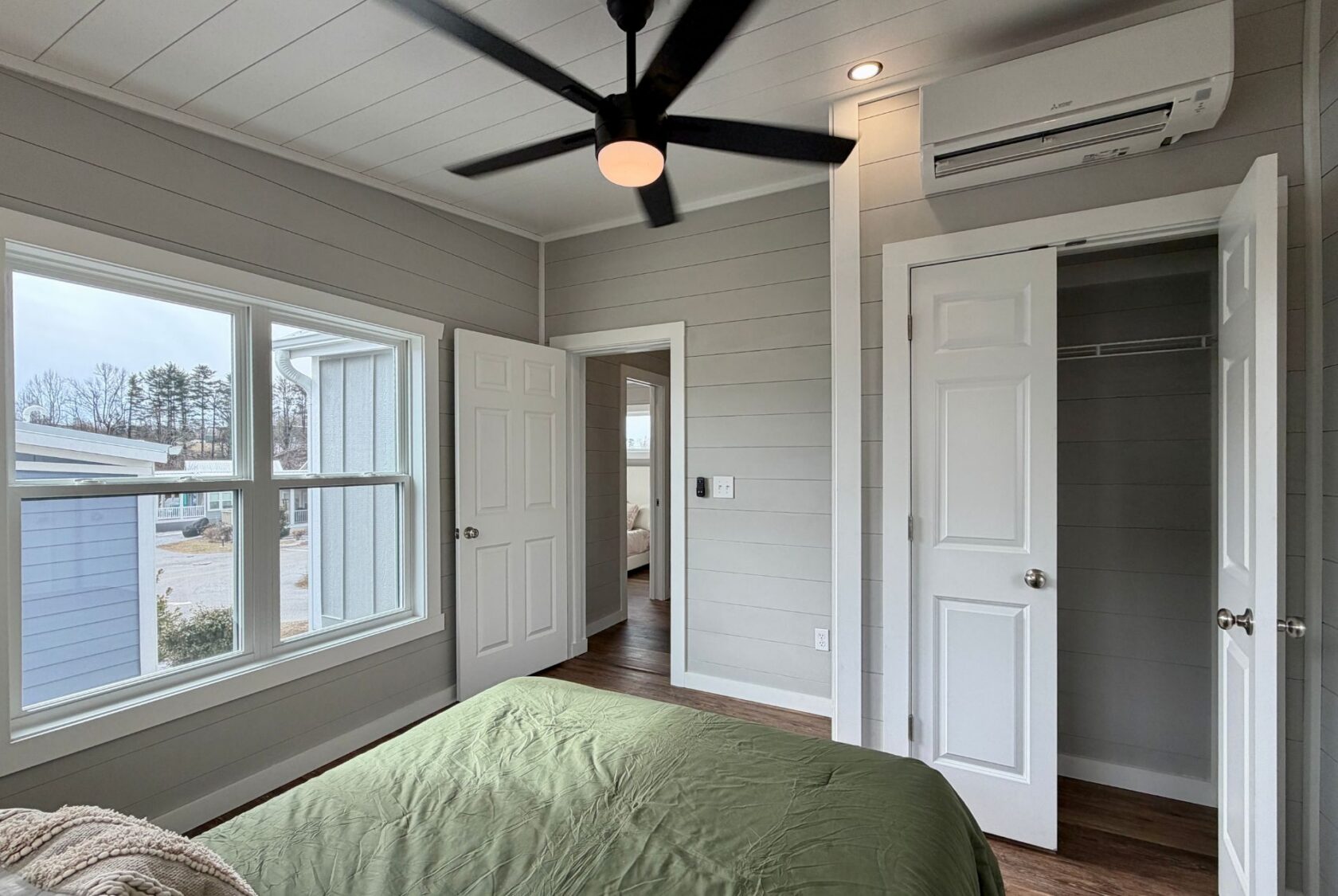Bright bedroom at 124 Misty Knoll Way with gray walls, green bedspread, ceiling fan, and large windows.