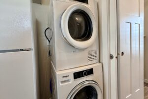 Stacked washer and dryer units next to a white refrigerator—laundry day on Strolling Easy Lane.