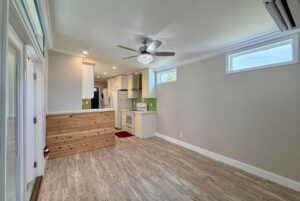 Modern small kitchen and living area with wood flooring, white cabinets, and a Strolling Easy Lane vibe.
