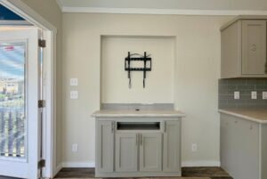 Gray cabinet with marble top under a TV wall mount in a recessed alcove at 40 Easy Lane, next to a door and switches.