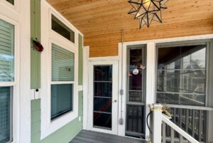A porch on Strolling Easy Lane with green and white walls, windows, glass door, and a star-shaped light overhead.