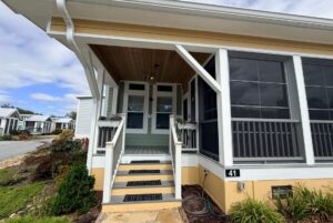 Yellow house on Strolling Easy Lane with a covered porch, screened windows, and number 41 by the entrance steps.
