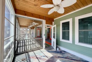 Screened-in porch with ceiling fans, wood ceiling, and green walls—welcome to Strolling Easy Lane.