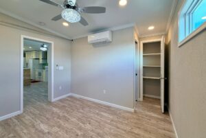 Small room with wood floors, ceiling fan, closet, and open door to a kitchen—your Strolling Easy Lane retreat.