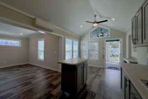 Modern open-concept kitchen and living area on Strolling Easy Lane with wood floors, large windows, and a ceiling fan.