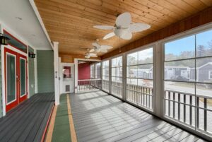 Screened porch with ceiling fans, wooden ceiling, red doors, and a relaxing Easy Lane view for strolling outside.