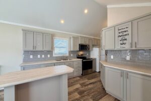 Modern kitchen with gray cabinets, stainless steel appliances, and a small island on Easy Lane wood flooring.