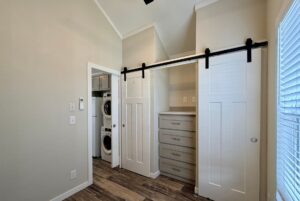 Room on Strolling Easy Lane with sliding barn doors, built-in drawers, and a laundry area with stacked washer and dryer.