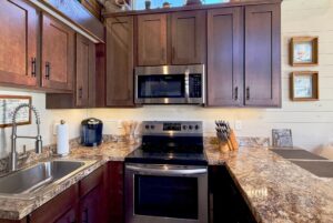 A modern Highland Hollow Lane kitchen with dark wood cabinets, stainless steel appliances, and marble countertops.