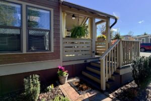 Small porch with stairs, potted plants, and fern outside a brown house on Highland Hollow Lane, sunlit and inviting.