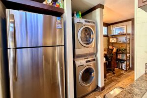 Stainless steel fridge, stacked washer-dryer, and cozy home office in a Highland Hollow Lane residence.