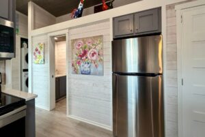 Modern kitchen on Mount Meadow Lane with stainless steel fridge, floral art, and stacked washer and dryer.