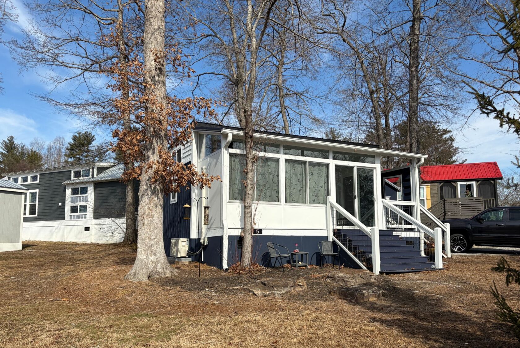 A small blue and white house with a front porch sits on Empire Lane, surrounded by outdoor chairs and leafless trees.