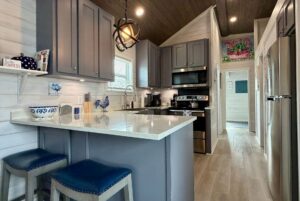 Modern kitchen on Mount Meadow Lane with gray cabinets, white countertops, and two blue stools at the breakfast bar.