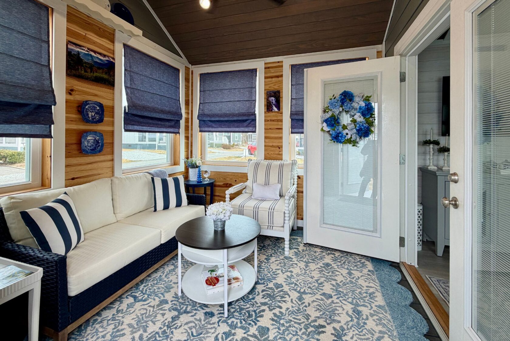 Cozy sunroom at 86 Mount Meadow Lane with navy and white decor, striped furniture, and blue roman shades.
