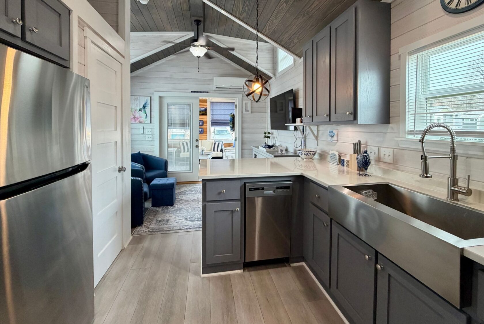 Modern kitchen with gray cabinets, stainless appliances, and view into cozy living on Mount Meadow Lane with blue sofa.