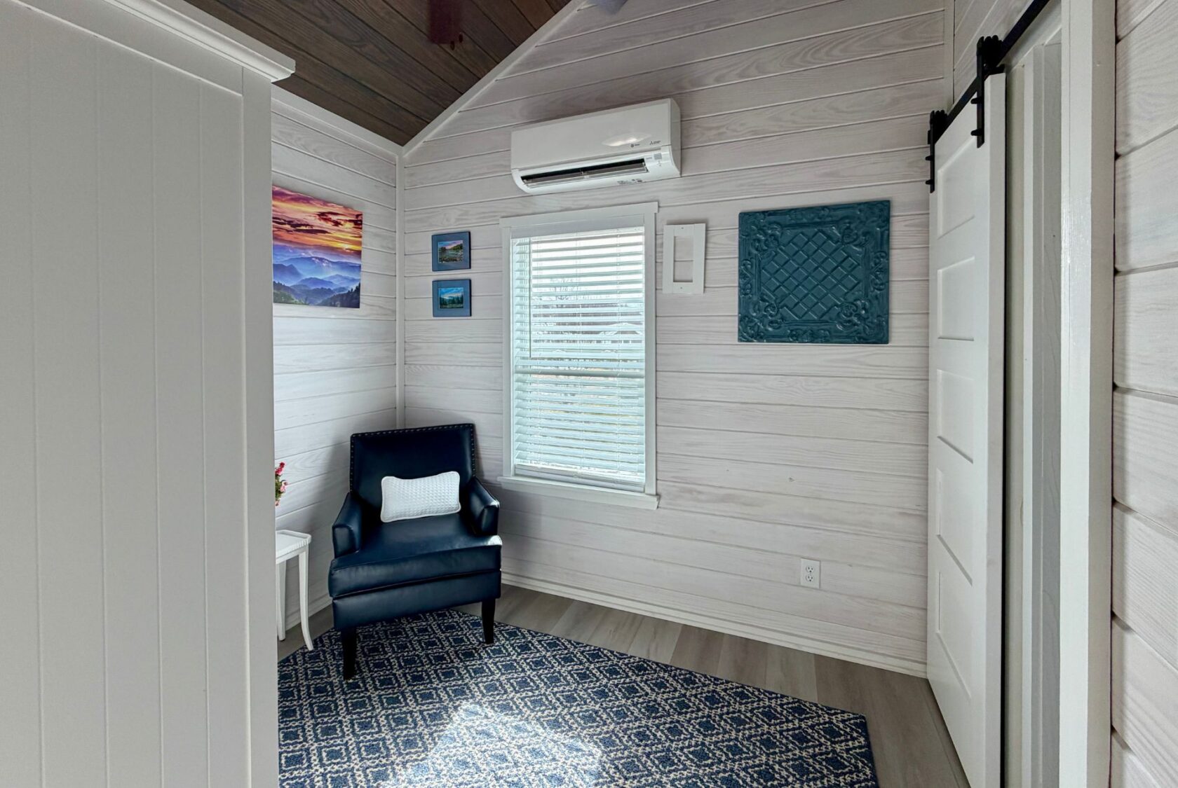 Cozy room at 86 Mount Meadow Lane with a blue armchair, window, wall art, and a blue-patterned rug on light wood floors.