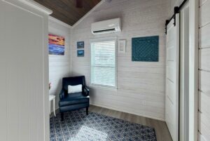 Cozy room at 86 Mount Meadow Lane with a blue armchair, window, wall art, and a blue-patterned rug on light wood floors.
