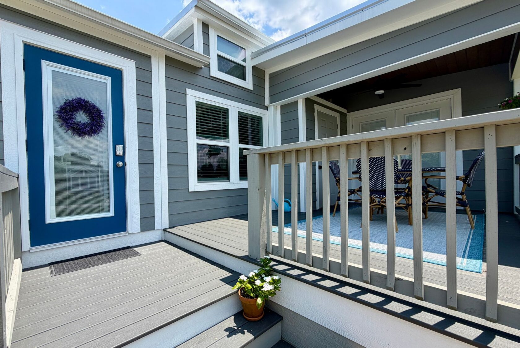 Modern gray house on Mount Meadow Lane with a blue door, potted flowers, and a cozy covered porch.