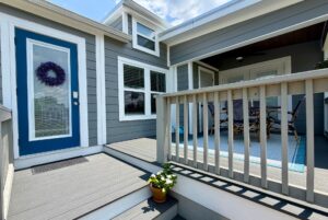 Modern gray house on Mount Meadow Lane with a blue door, potted flowers, and a cozy covered porch.