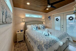 Cozy bedroom on Mount Meadow Lane with a large bed, floral bedding, wall art, and glass doors with wreaths.