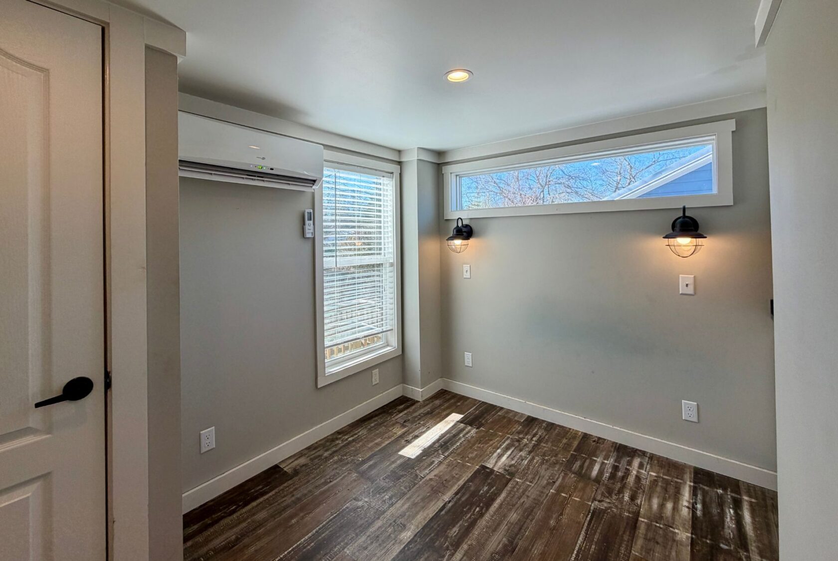 Small, empty room at 139 Drifting Brook with wood flooring, wall lights, window blinds, and air conditioner.