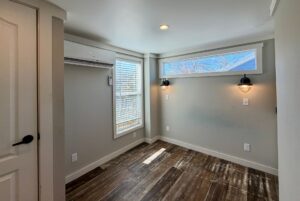 Small, empty room at 139 Drifting Brook with wood flooring, wall lights, window blinds, and air conditioner.