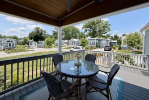 Covered porch with round glass table and four chairs, overlooking Mount Meadow Lane's small modern homes.