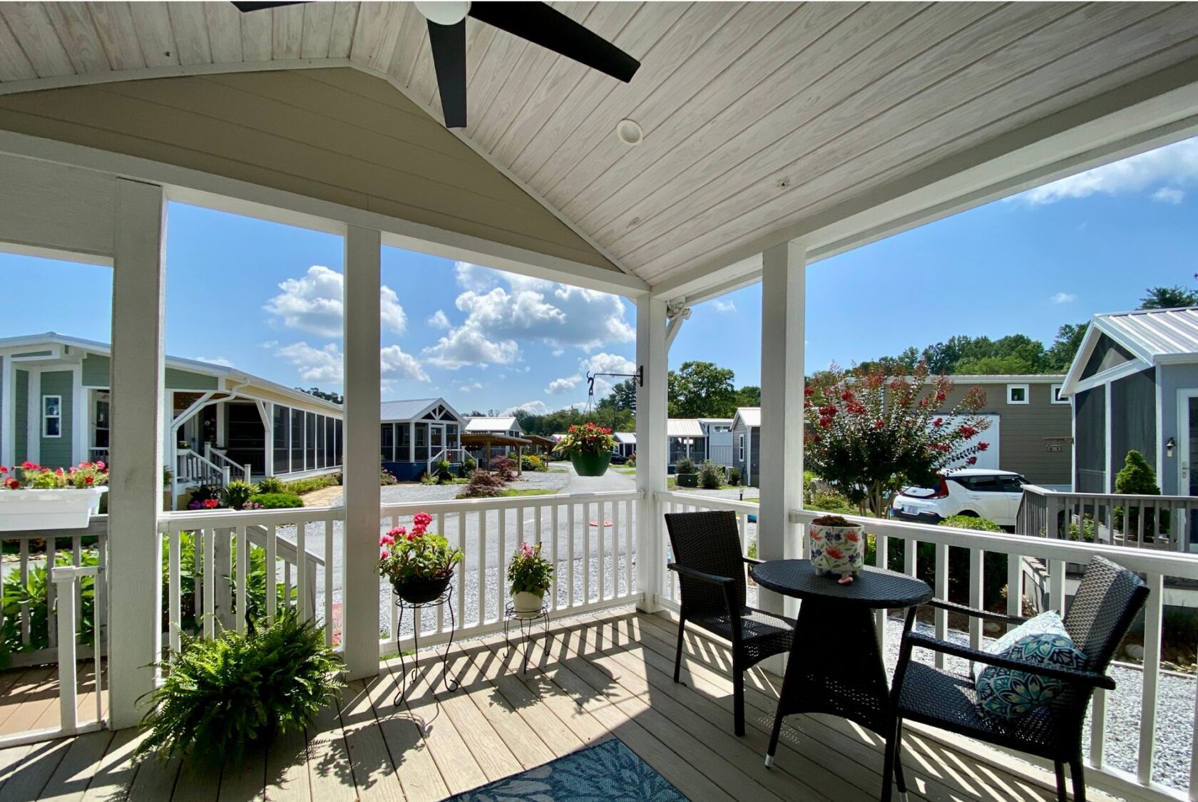 Covered porch on Easy Lane with table, chairs, potted plants, and views—perfect for strolling on a sunny day.