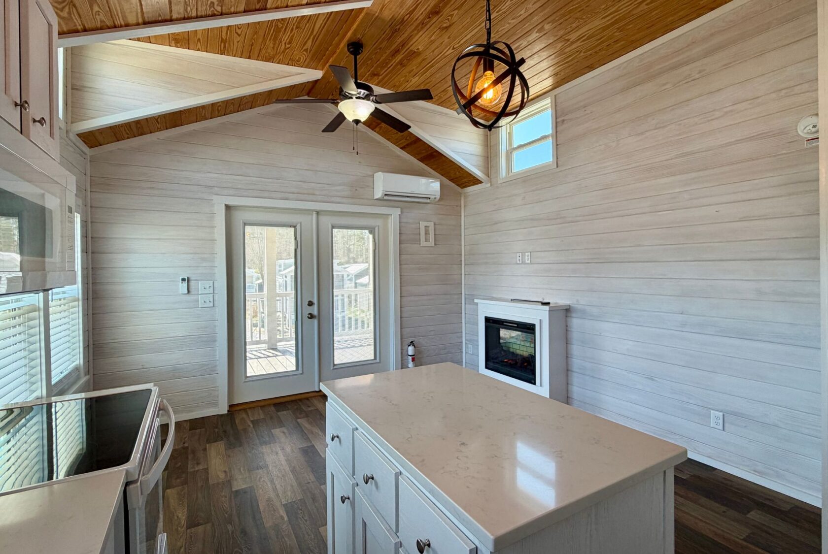 Bright kitchen at 119 Breezy Meadow Lane with wood ceiling, island, fireplace, and French doors to the deck.
