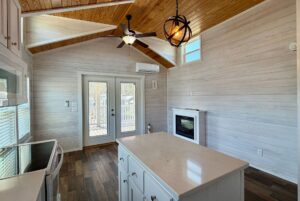 Bright kitchen at 119 Breezy Meadow Lane with wood ceiling, island, fireplace, and French doors to the deck.