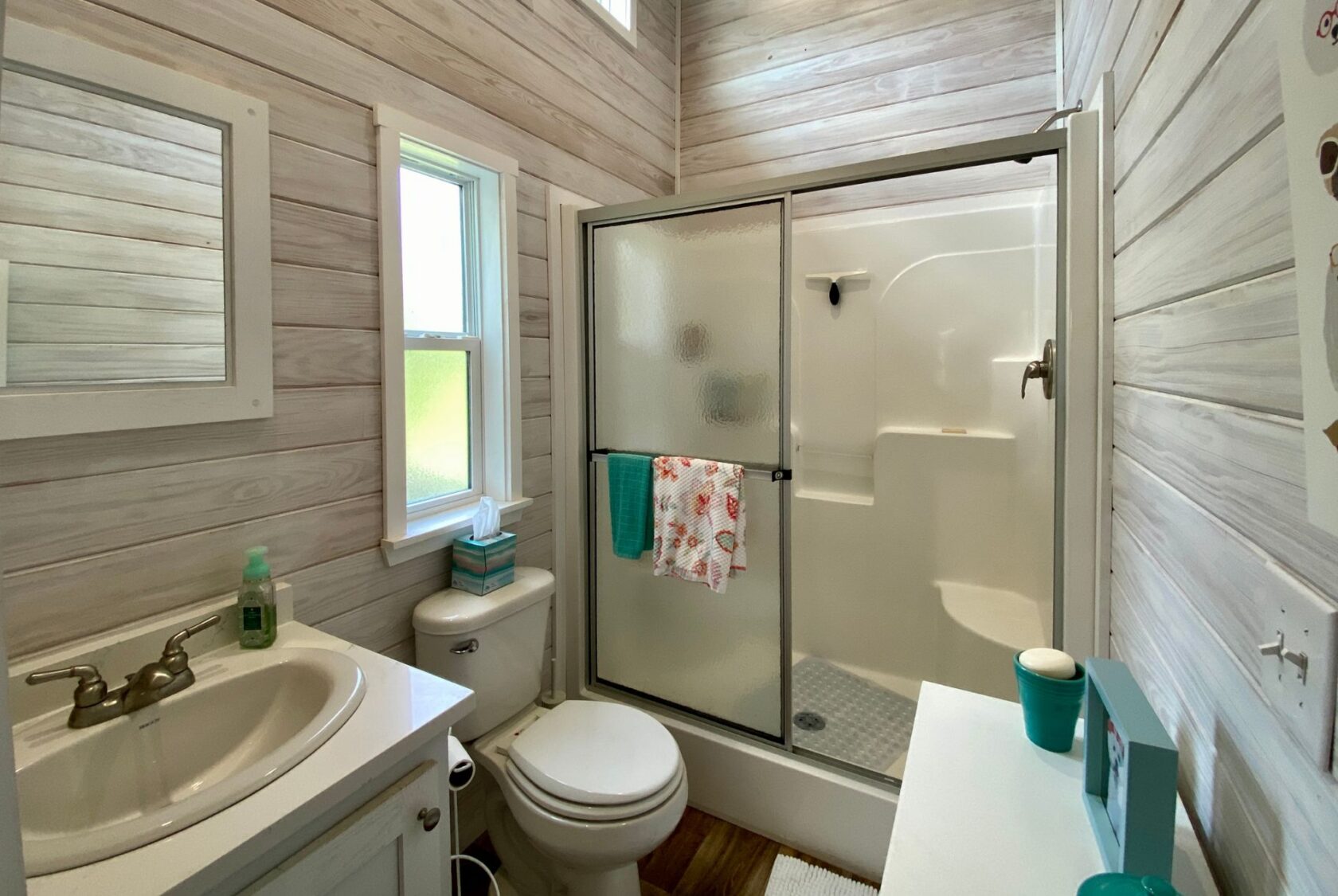 Small bathroom with wood-paneled walls, white fixtures, and a shower—perfect for strolling Easy Lane at home.
