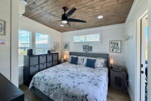 Cozy bedroom on Mount Meadow Lane with a large bed, wooden ceiling, modern decor, and sunlight streaming in.
