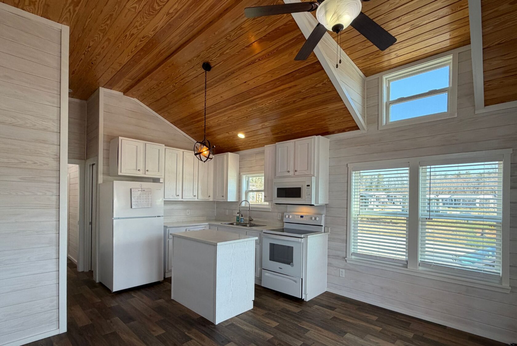 Kitchen with white cabinets, island, wood ceiling, and sunlit windows at 119 Breezy Meadow Lane real estate.