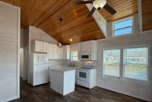Kitchen with white cabinets, island, wood ceiling, and sunlit windows at 119 Breezy Meadow Lane real estate.
