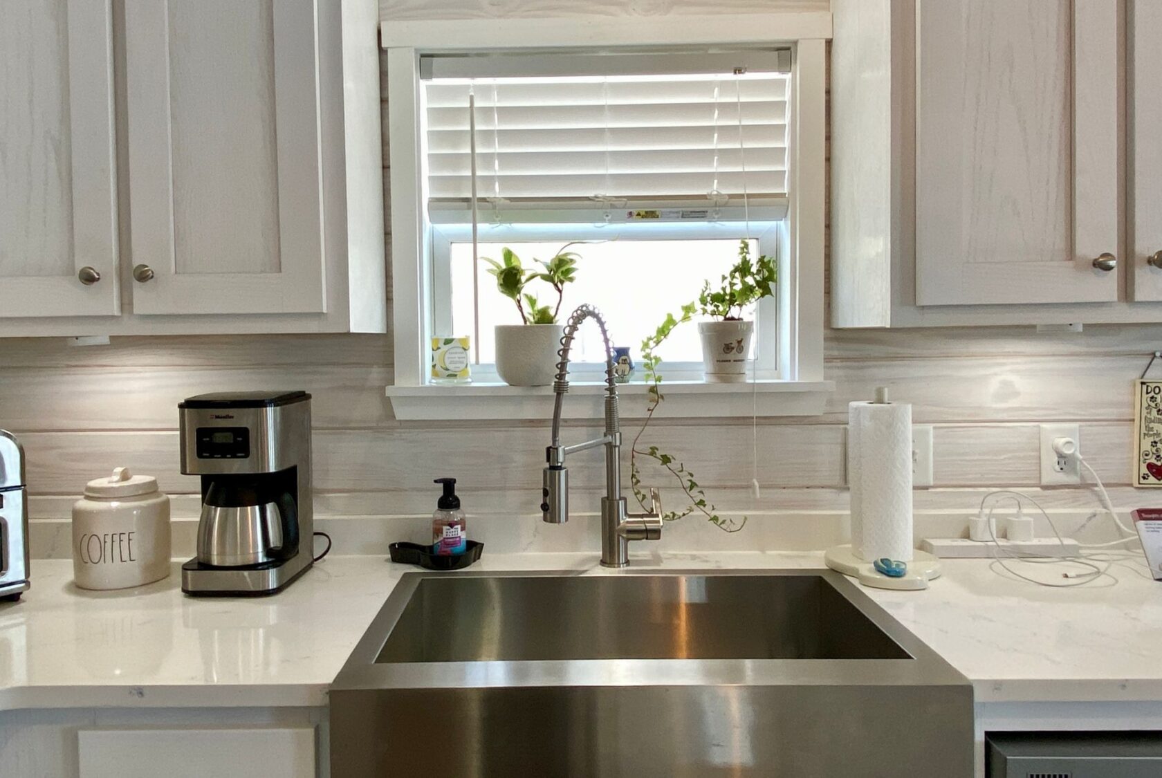 Modern kitchen sink with a faucet, coffee maker, and potted plants for that Strolling Easy Lane kitchen vibe.