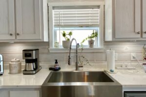 Modern kitchen sink with a faucet, coffee maker, and potted plants for that Strolling Easy Lane kitchen vibe.