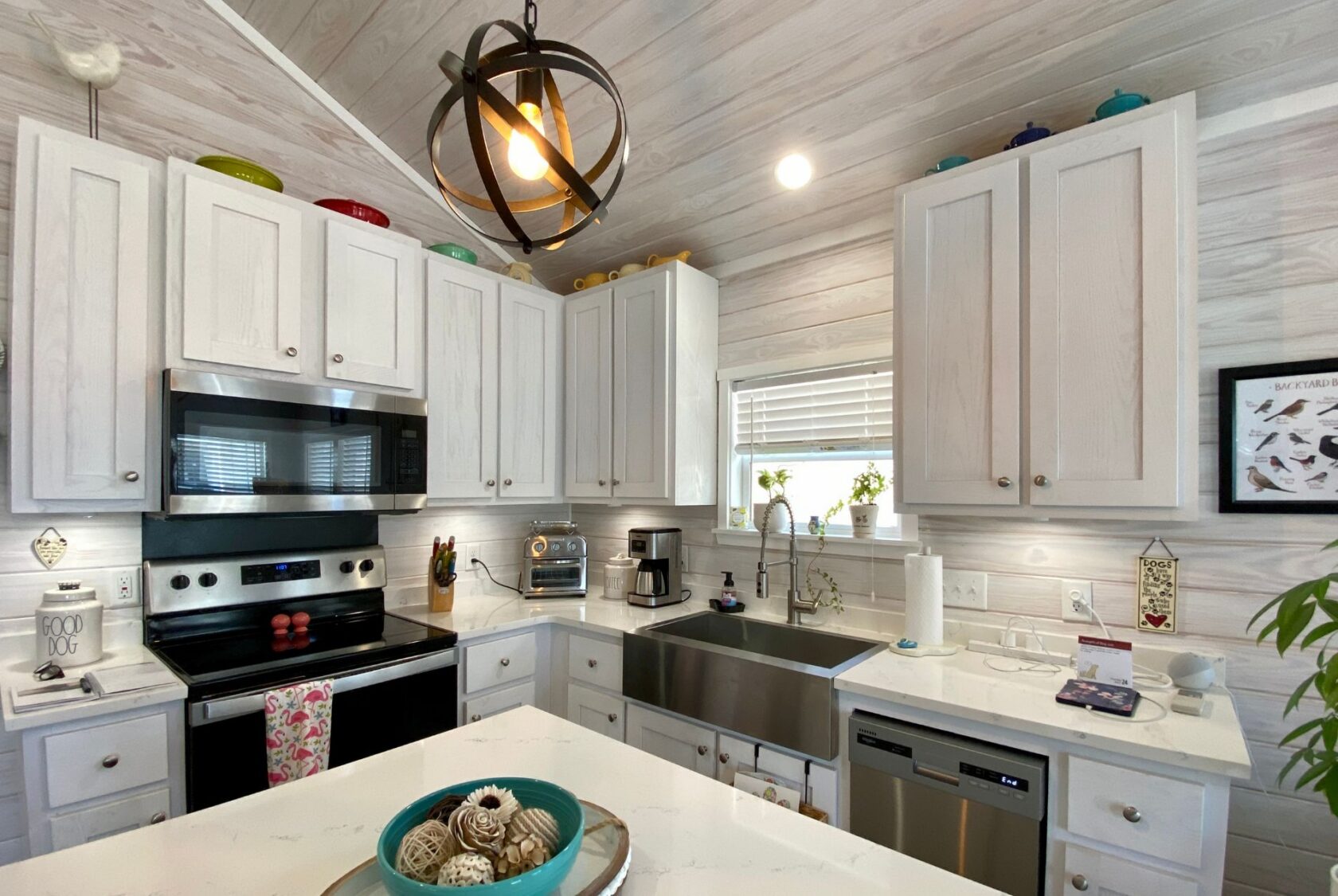 Bright kitchen with white cabinets, stainless appliances, and a bowl of seashells—perfect for Strolling Easy Lane living.