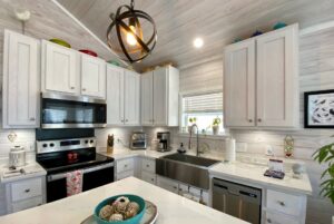 Bright kitchen with white cabinets, stainless appliances, and a bowl of seashells—perfect for Strolling Easy Lane living.